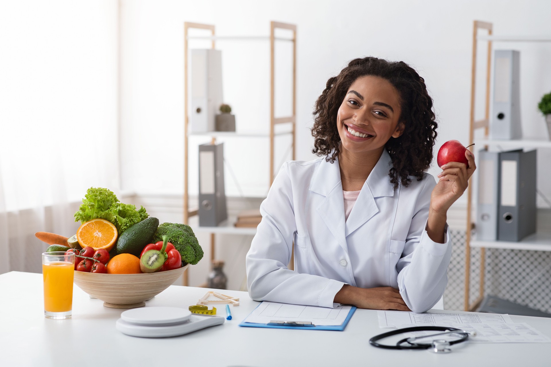 Pretty female dietologist holding apple in her hand and smiling